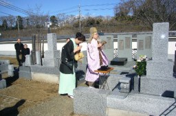 記念碑（奥）の完成を堅曹の墓前で報告する美智子さん（左）