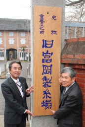 門柱に掲げた看板と須賀会長（左）