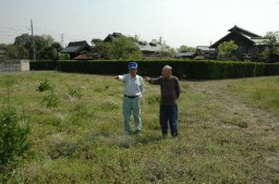 桑畑の整備予定地に立つ田島会長（右）と栗原さん。後ろは田島会長宅