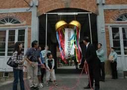 岡野市長と記念のくす玉を割る井坂さん一家（左側） 