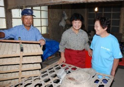 昨年まで使っていた養蚕道具を手にする矢田堀さん夫妻と中村さん（右） 