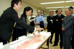 模型で駅舎を説明する武井さん（左）と鍋島さん（左から２人目） 