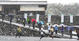 降りしきる雪の中、高山社跡前を力走する出場者 