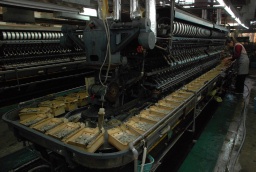 機械音を響かせて繭から糸を引く繰糸機。富岡製糸場に展示されているものと同型が使われている＝碓氷製糸 