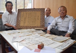 資料を探し当てた神戸さん（右）と所有していた工藤さん（中央）、贈呈を受けた市川宣夫村長 