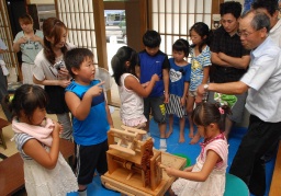 町田さん（右）から説明を受け、座繰りを体験する子どもたち 