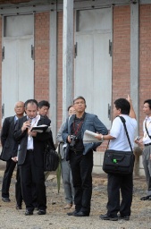 富岡製糸場の西繭倉庫前で、カメラを手に説明を聞くイコモス調査員の趙氏＝25日午前10時40分ごろ