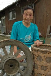 「この車輪と竹かごは養蚕をしていた証し」と話す立川さん。後ろは蚕室として使った２階屋