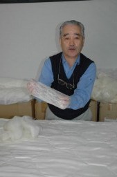 絹の袋真綿を手に、シルク布団の品質について語る富沢さん