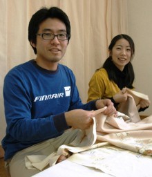 足の指で布を引っ張りながら縫う和浩さん（左）と針山を使って縫う由理さん 