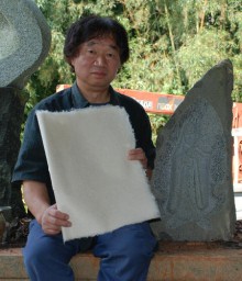 自ら作った絹の紙を持つ倉田さん。右は「絹神様」像