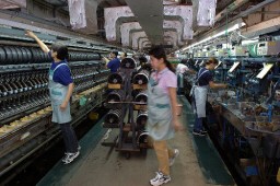 職員が慌ただしく作業する碓氷製糸の工場内部。県内唯一、全国でも２つしかない器械製糸場として、製糸業の灯を守っている